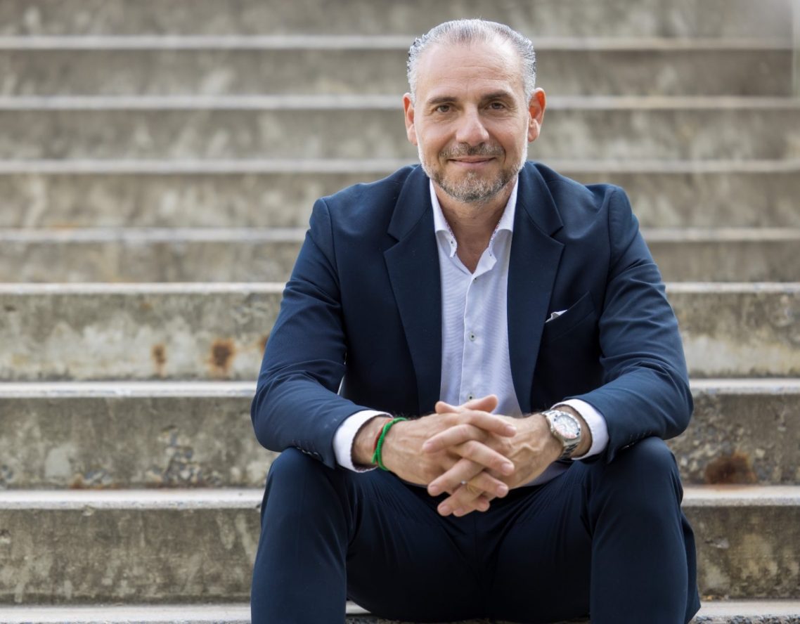 Francesco Strigari im Anzug, freundlich lächelnd vor unscharfem Hintergrund – steht für Klarheit, Vertrauen und professionelle Beratung